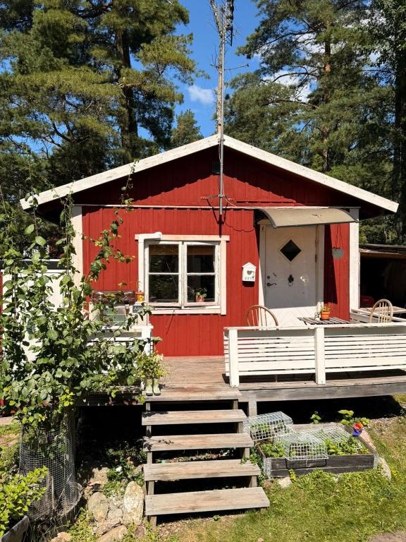 a red shed with a porch and a deck at Tiny house at Enhrna in Enhörna
