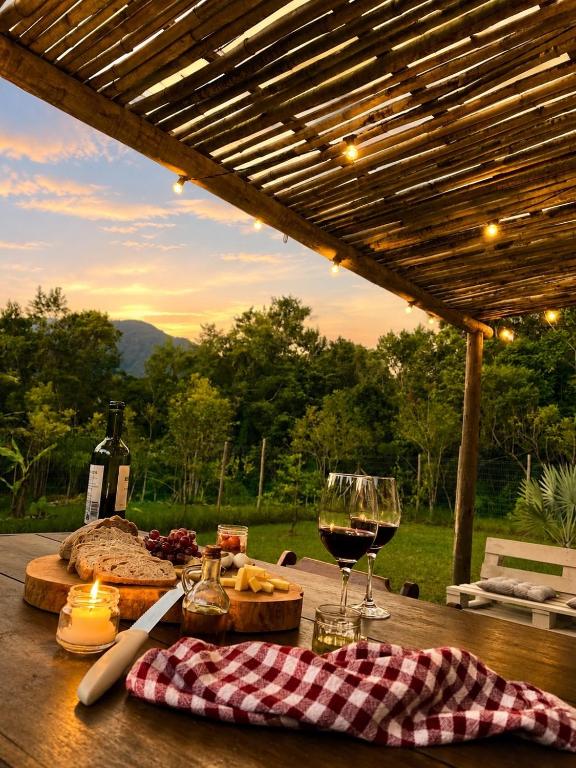 a wooden table with a glass of wine and cheese at Jardim Mirim in Cananéia
