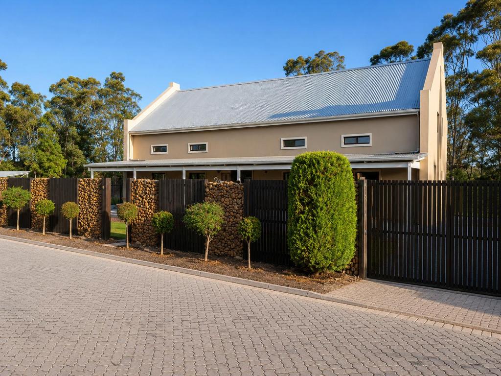 a house with a black fence and bushes at The Upper Deck Apartment in Swellendam