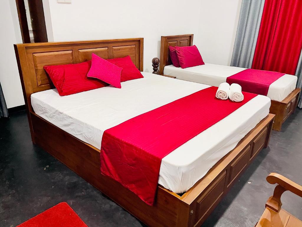 two beds in a room with red pillows at Double T in Dickwella