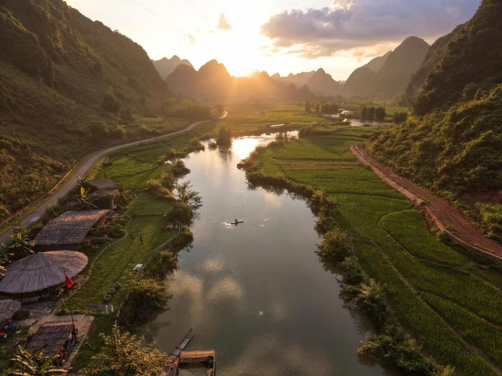 a river with a boat in a valley with mountains at Phong Nam Station in Bản Piên