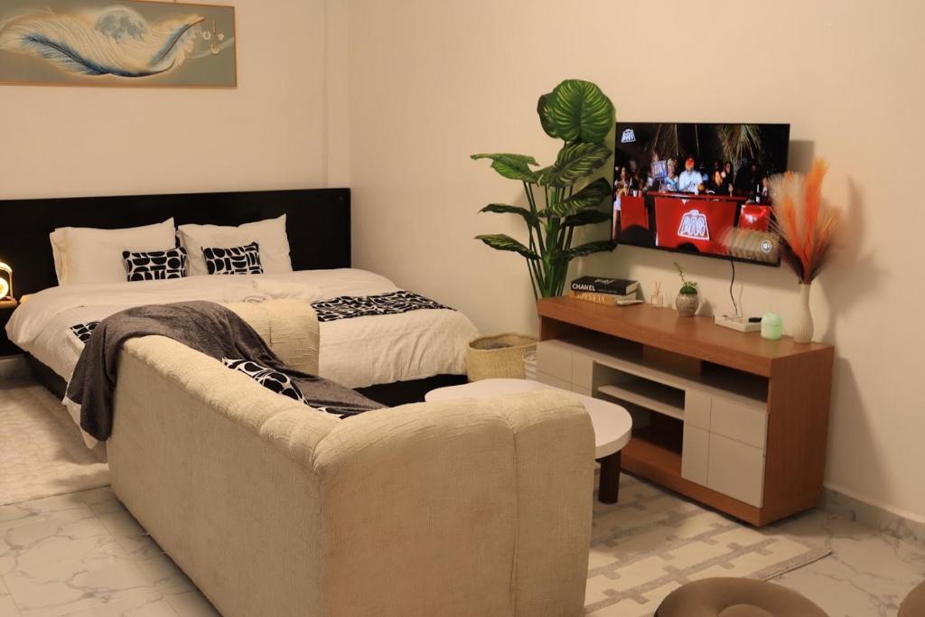 a bedroom with a bed and a couch and a tv at Kilimavista Homes studio D2 in Kimana