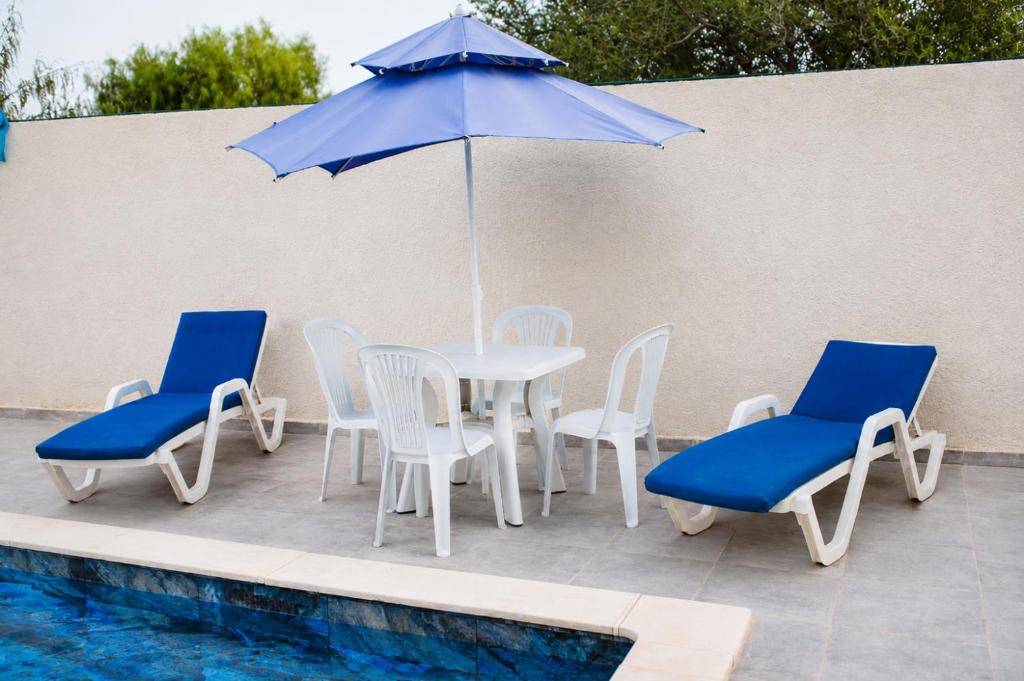 a table with chairs and an umbrella next to a pool at Villas avec piscine in Taguermess
