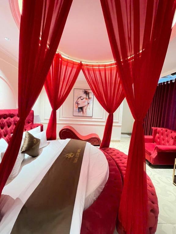 a bedroom with red curtains and a bed and a couch at Grand Hotel & Spa Bac Ninh in Ðồng Ky