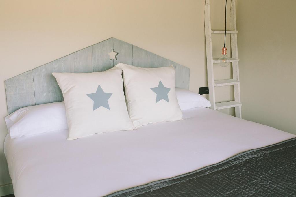 Una cama con cuatro almohadas con estrellas. en ALTAIR Turismo Rural, en Béjar
