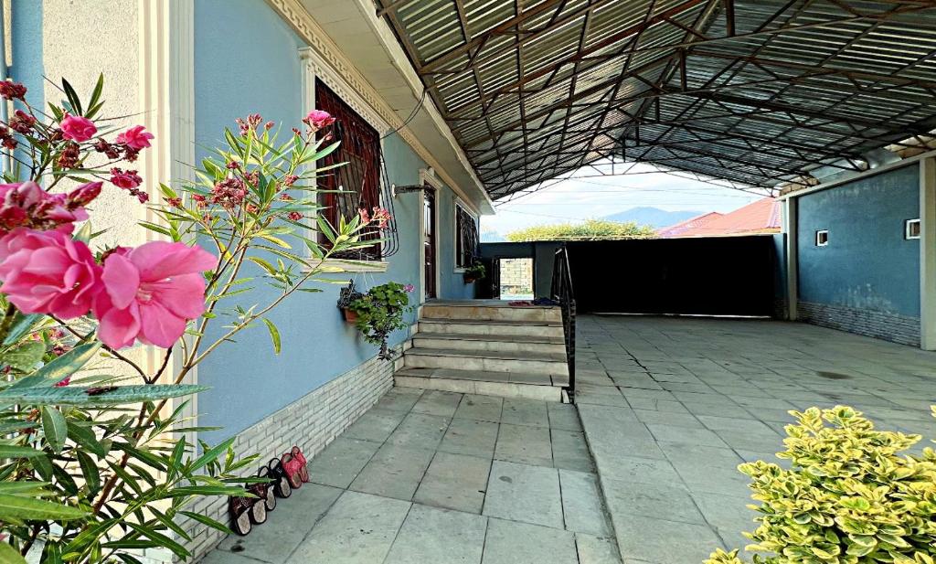 a porch of a house with pink flowers and stairs at Gabala Grean Villa in Gabala