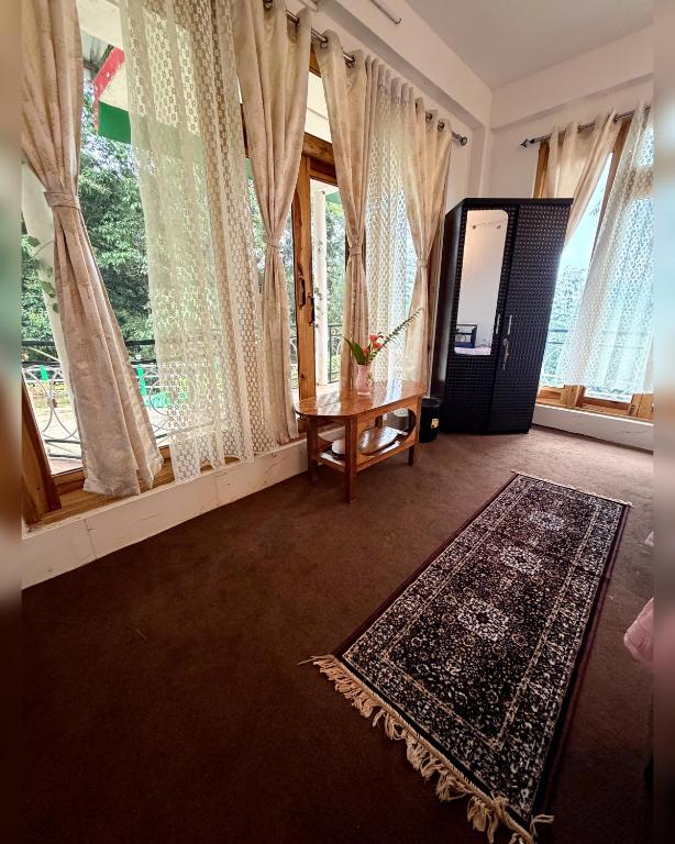 a living room with a rug and windows at Kepchaki Stay in Takdāh
