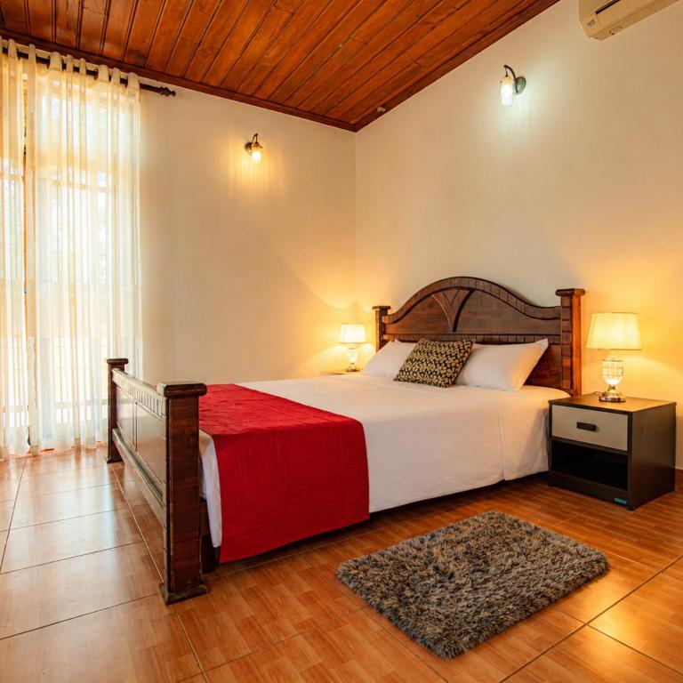 a bedroom with a large bed with a red blanket at Airport Serenity Villa - Near Colombo Airport in Katunayaka