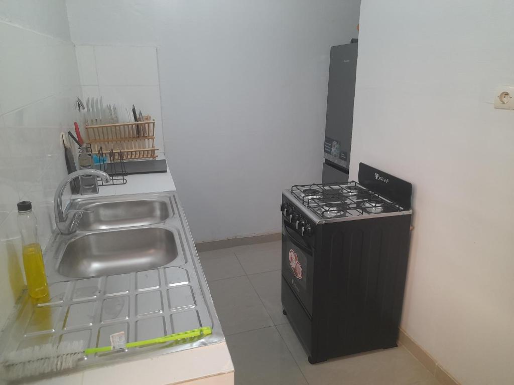 a kitchen with a sink and a stove at Residence du fromager in Bouaké