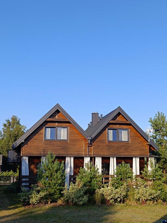 a large wooden house with a gambrel at Szumiące Drzewa in Debina
