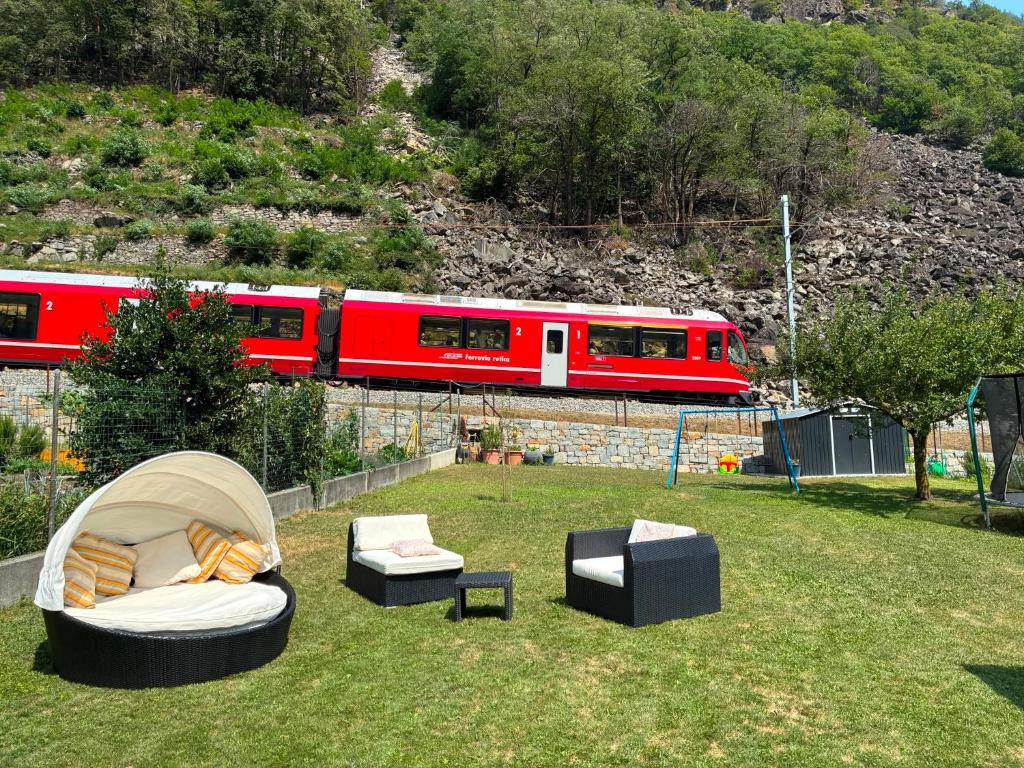 a red train traveling past a yard with couches and chairs at Casa Lucini in Campascio