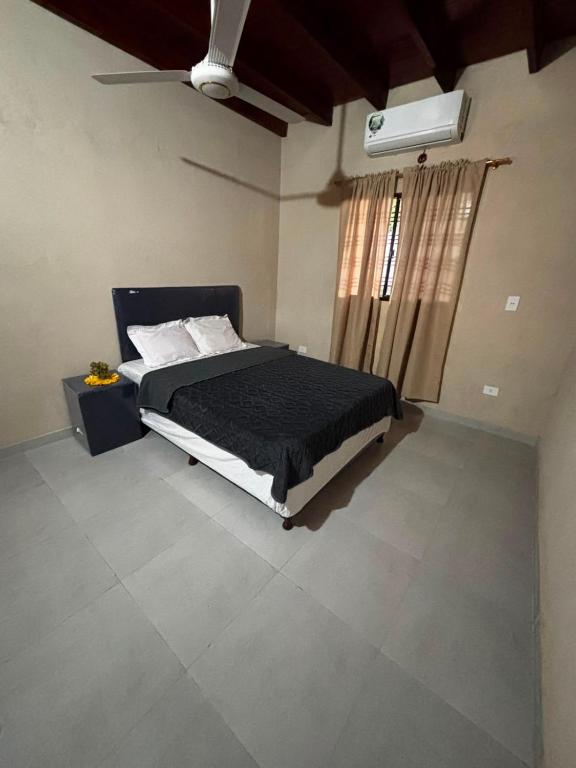 a bedroom with a bed and a window with a fan at Monoambiente en villa Elisa in Villa Elisa
