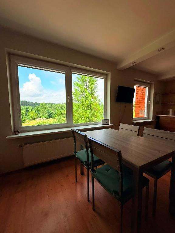 a dining room with a table and chairs and a large window at Līgatne Forest View Apartament in Skalupji