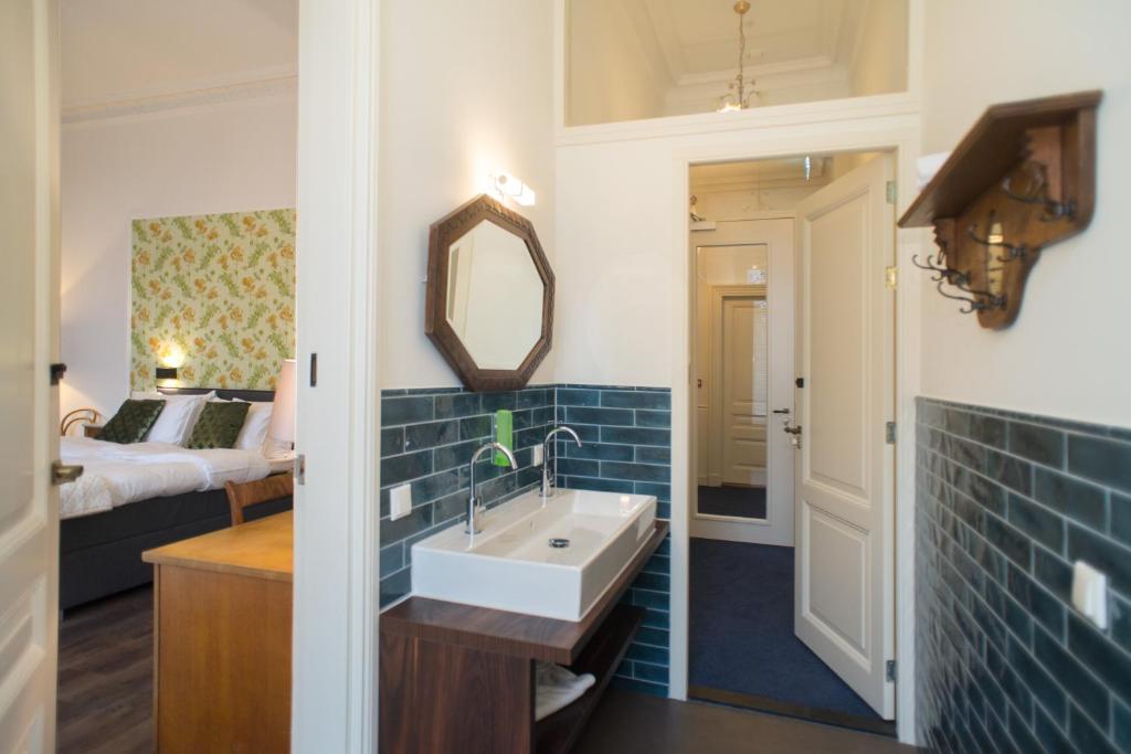 een badkamer met een wastafel, een bed en een spiegel bij Boutique Hotel De Blauwe Pauw in Den Bosch