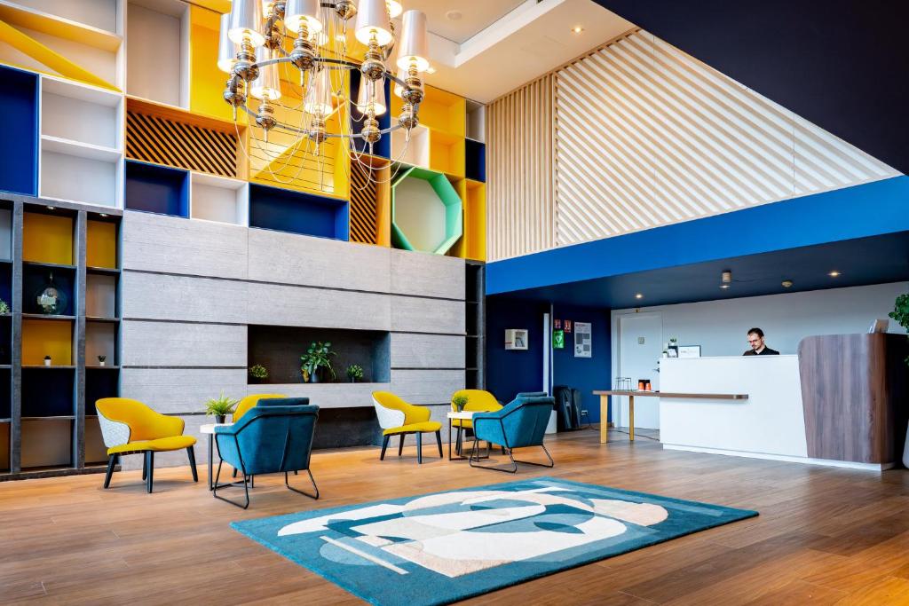 a lobby with chairs and a table and a counter at Holiday Inn Mulhouse by IHG in Mulhouse