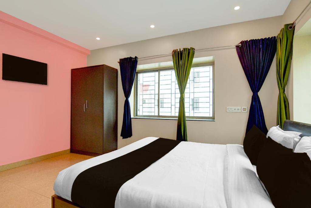a bedroom with a large bed with purple curtains at Hotel O Newtown worldstay in Thākurdwari