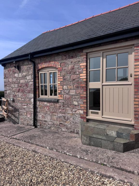 a stone house with a garage and a stone wall at The Barn With A View in Portskewett