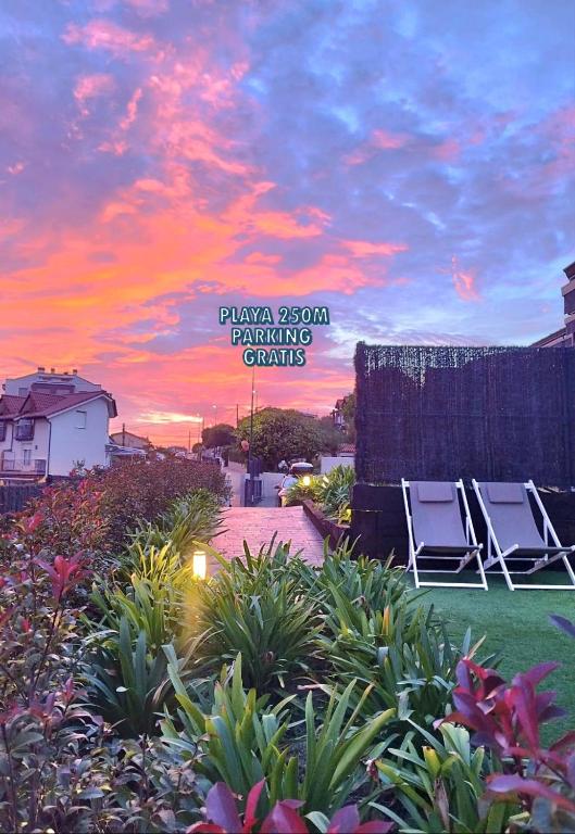 two lawn chairs sitting in a yard with a sunset at Apartamentos Las Terrazas de Suances in Suances