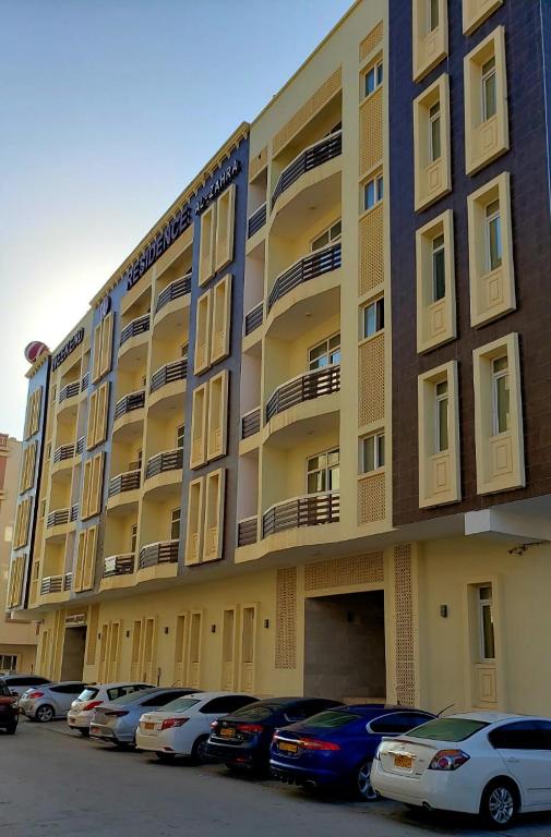 a large building with cars parked in a parking lot at Alzahraa apartment in Salalah