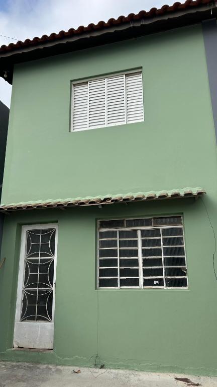 a white and green house with two windows at Casa Aconchegante com 2 quartos in Araçariguama