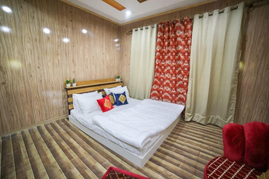 a bedroom with a bed and a red curtain at Royal Brangsa in Skardu