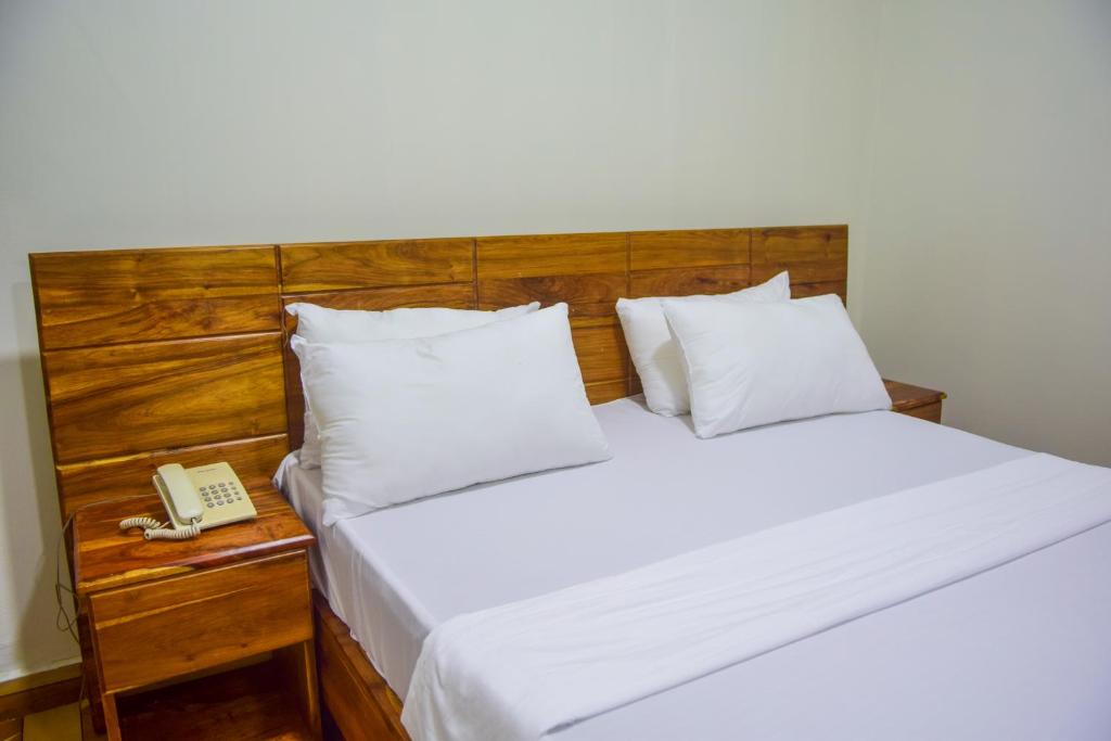 a bed with a wooden headboard and a telephone at N-line Residency Hotel in Arusha