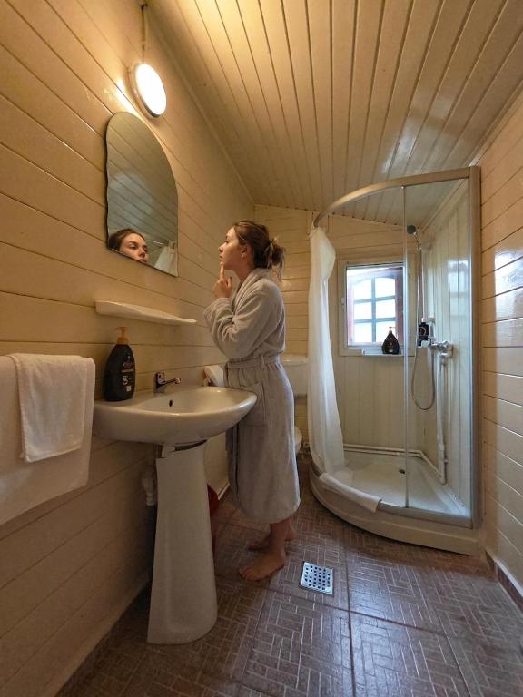 a woman standing in a bathroom with a sink and a shower at Mara by iVAVev in Eforie Sud