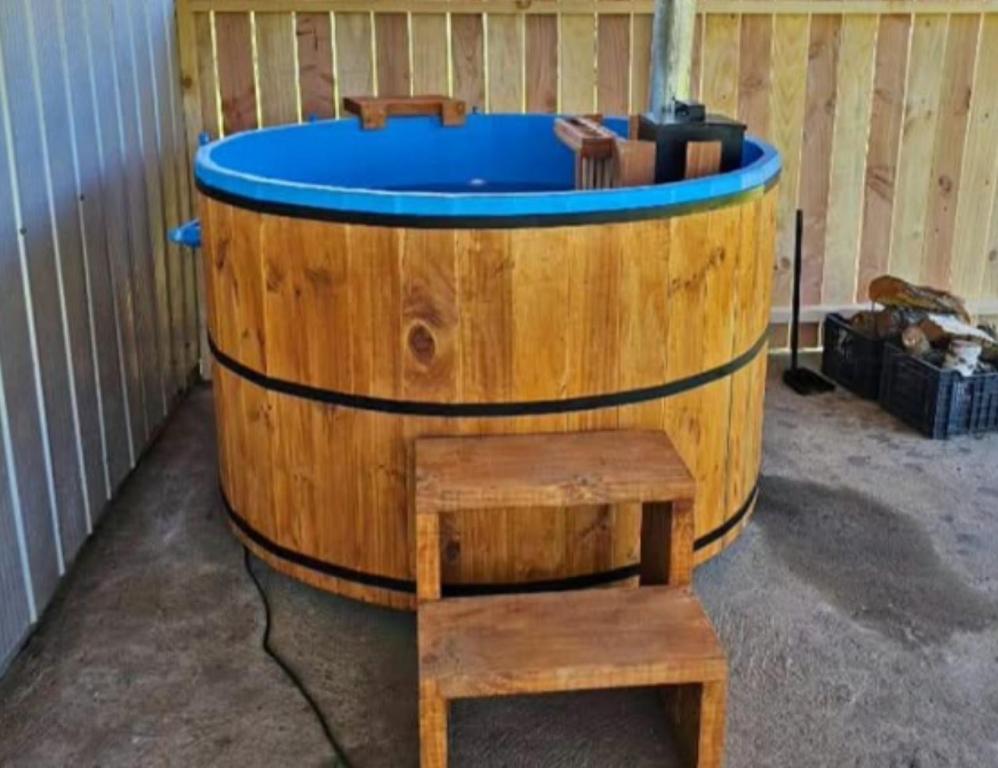 a wooden bath tub with a blue top and a bench at Hospedaje Canarias in Pucón