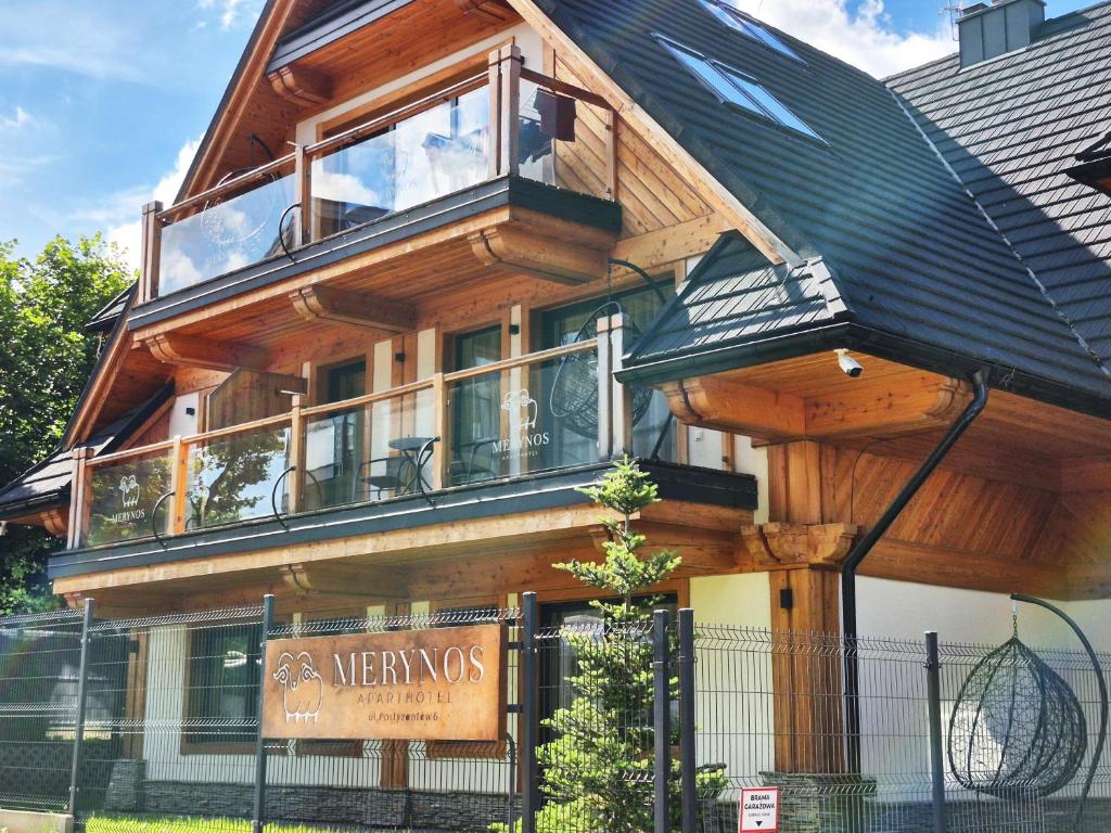 a wooden house with a balcony on top of it at Aparthotel Merynos in Zakopane