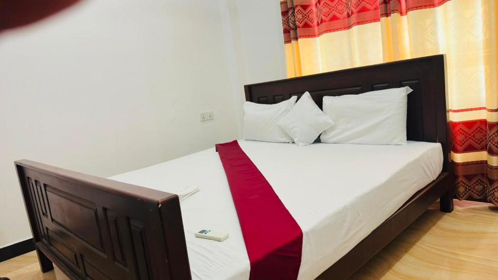 a bedroom with a bed with a red tie on it at Nilaveli Beach Haven in Nilaveli
