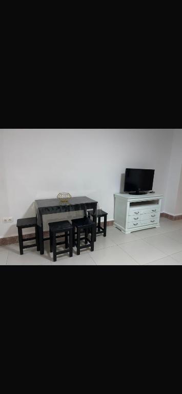 a living room with a table and benches and a tv at rahamni stays in Cheraga