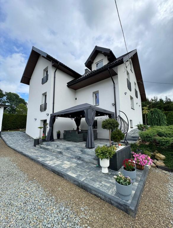 a white house with a patio with potted plants at Bieszczady Hill - Dolna in Czarna
