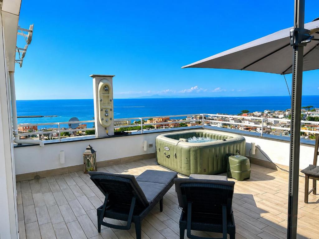 a balcony with a hot tub and chairs and the ocean at Victory's Luxury House with Jacuzzi on the Roof in Casamicciola Terme