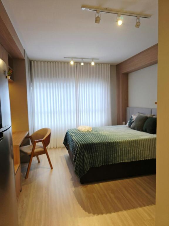 a bedroom with a bed and a table and a chair at Apê Calma - 5min Consulado EUA - Garagem in Porto Alegre