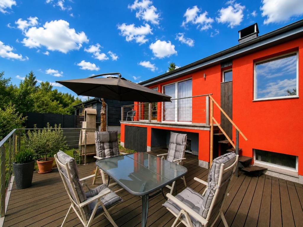 a deck with a glass table with chairs and an umbrella at Ski- und Wanderurlaub im Wald Ferienhaus Adlerblick in Schnett