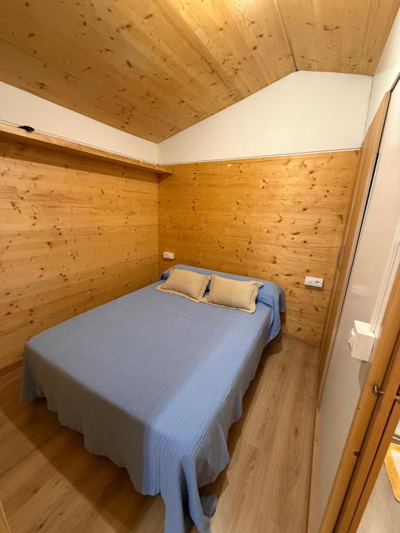 a bedroom with a bed in a wooden room at O Refuxio de Loira in Valdoviño
