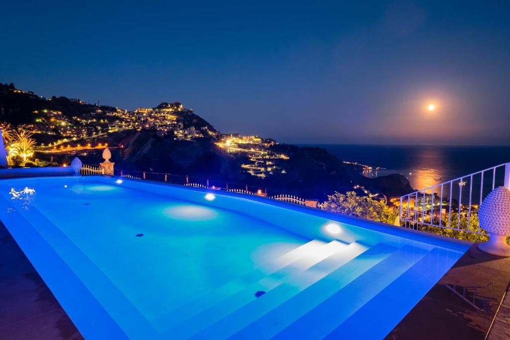 a pool with a view of the ocean at night at Sciccosa Guest House in Taormina