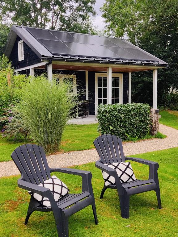 two chairs sitting in the grass in front of a house at Park De Driesprong in Nieuwveen
