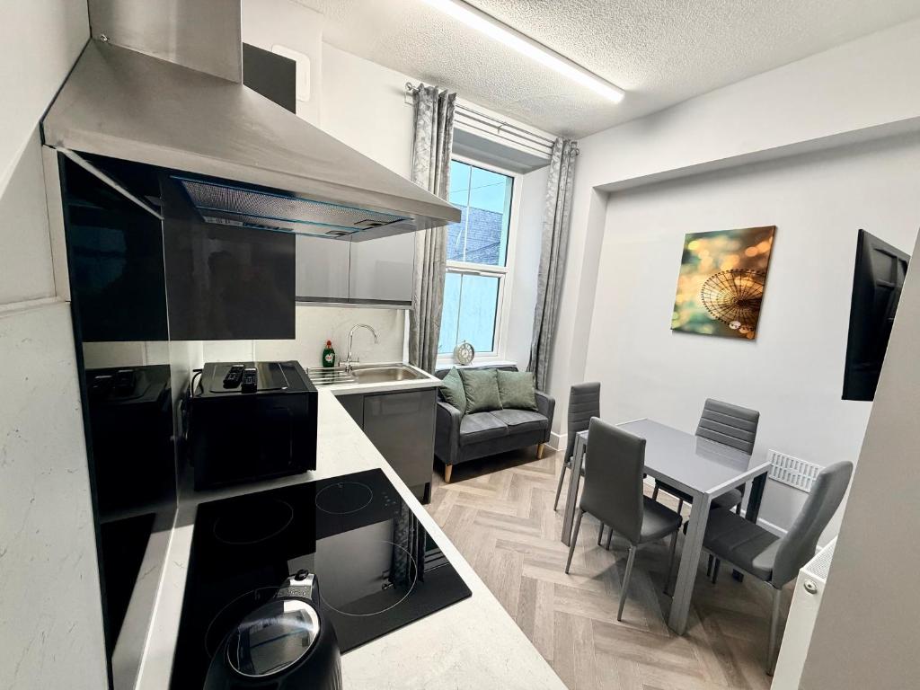 a kitchen and living room with a table and a stove at Homely Away in Plymouth