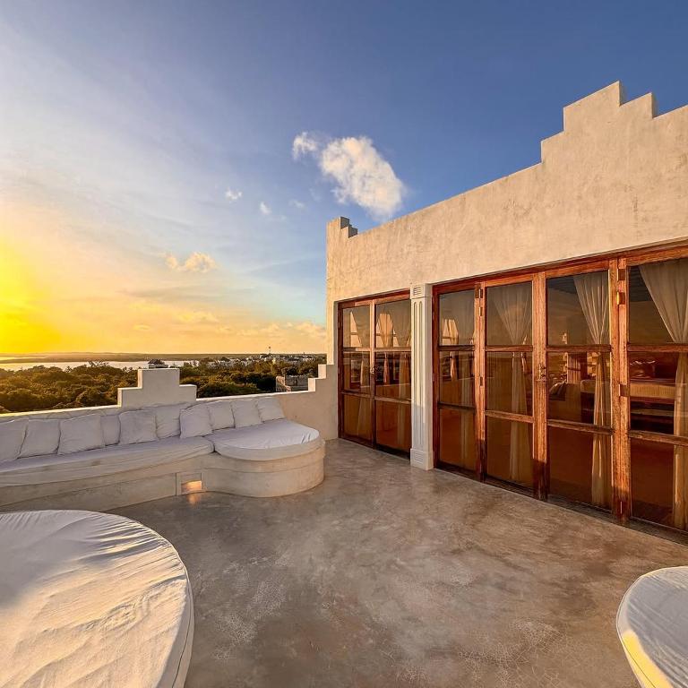 a building with a patio with a sunset in the background at Kilele House in Lamu