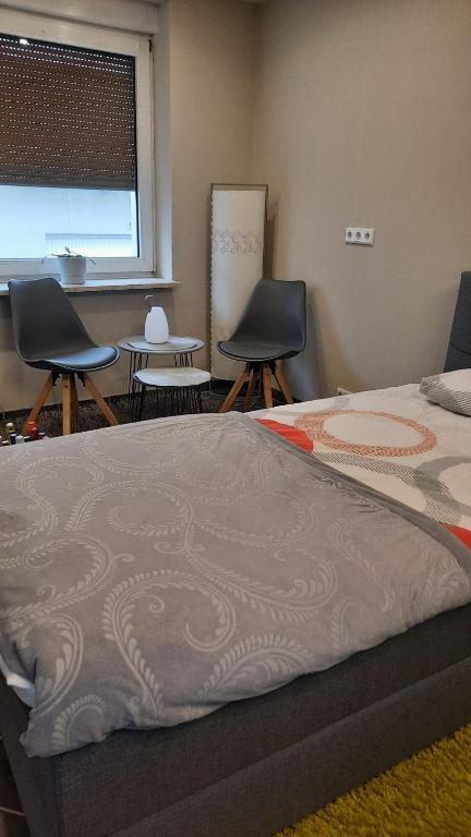 a bedroom with a bed and two chairs and a table at Gästezimmer Heinebach in Alheim