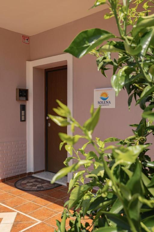 a plant in front of a door with a sign on the wall at Solena Residences in Syvota