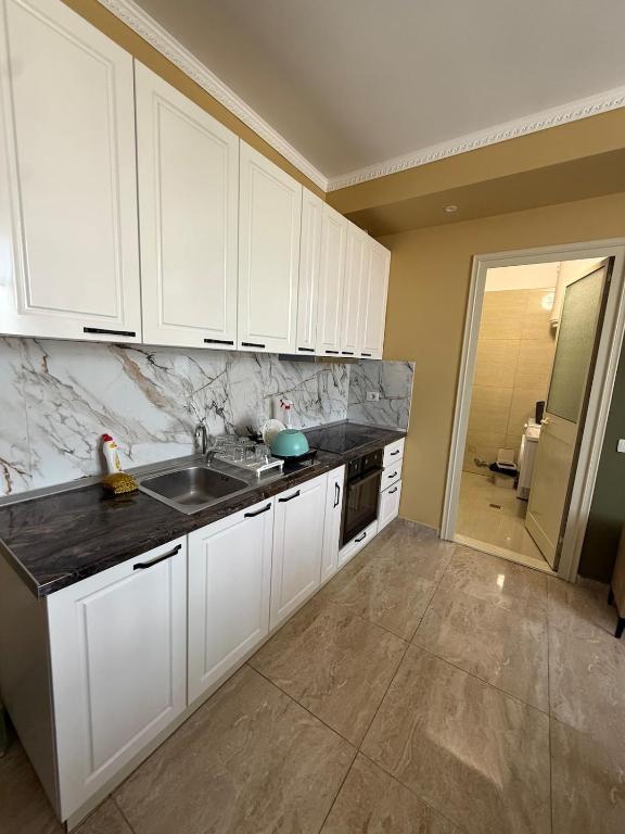 a kitchen with white cabinets and a sink at Durres-apartament in Durrës