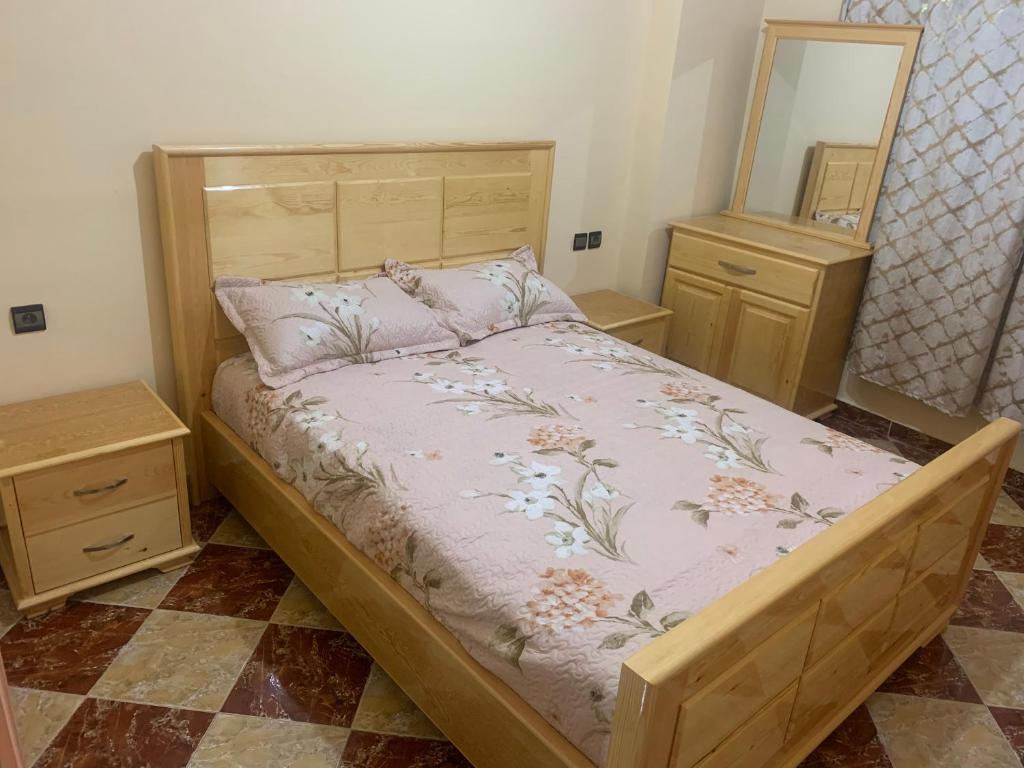a bedroom with a bed with a wooden frame and a mirror at Omarkad in Taourirt