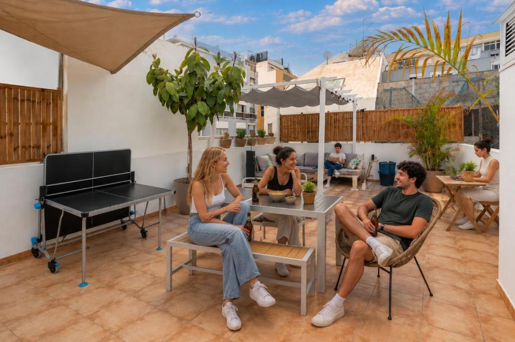 a group of people sitting at a table with a piano at Kite & Surf Nomad House in Las Palmas de Gran Canaria