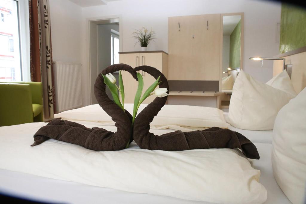 una camera d'albergo con asciugamani a due cigni su un letto di Goldener Schlüssel mit Gästehaus Sina a Nördlingen