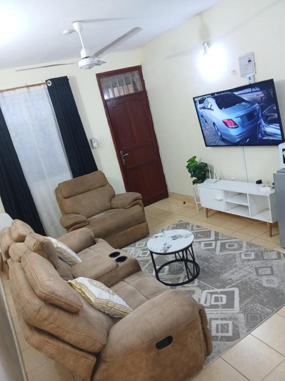 a living room with a couch and a flat screen tv at Lex homes in Mombasa