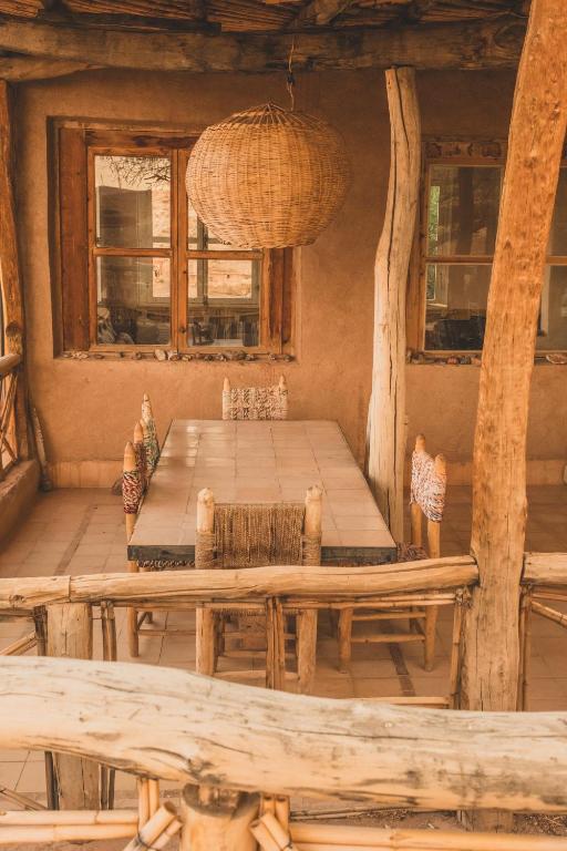 a wooden table and chairs in a room with windows at Maison d'Hôtes Irocha in Tisseldeï