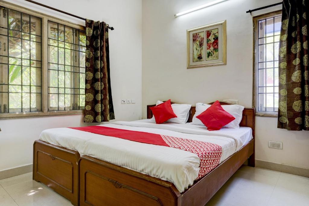 a bedroom with a large bed with red pillows at Hotel O J2 Service Apartment in Chennai