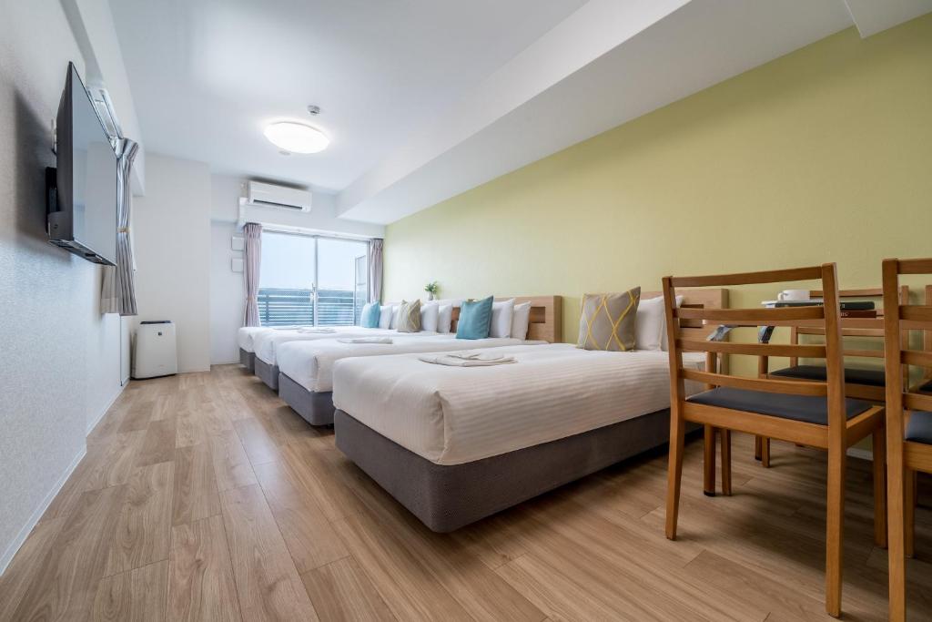 a row of beds in a room with a tv at ESLEAD HOTEL Namba South Ⅲ in Osaka
